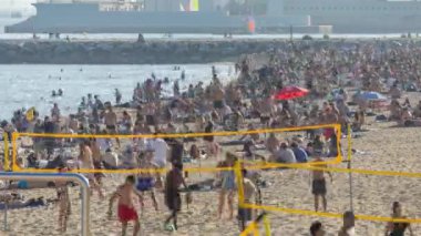 Öğleden sonra Barselona sahilinde plaj voleybolu oynayan insanların zamanı.