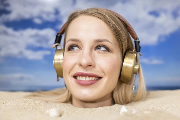 Uma Mulher Bonita Enterrada Cabeça Uma Praia Ouvindo Música Fones — Fotografia de Stock