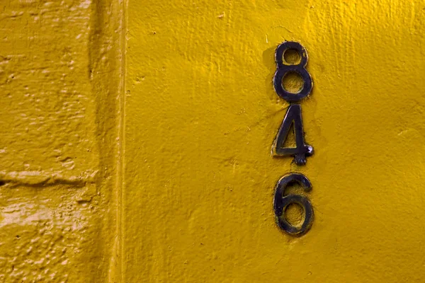 Números pretos velhos em uma parede amarela — Fotografia de Stock