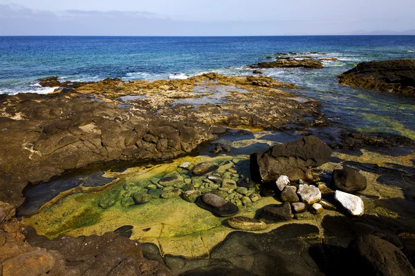 ランサローテ島スペインのビーチの水海岸線雲の石の石 — Stock fotografie