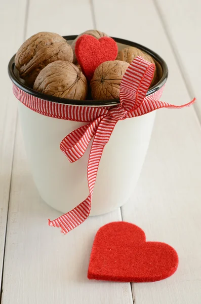 Walnuts in white cup and two red hearts — Stock Photo, Image