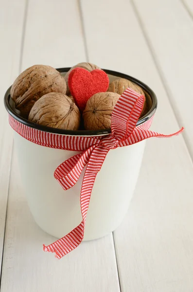 Орехи в белой чашке, ограниченной красной лентой и луком — стоковое фото