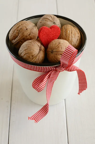 Walnuts in white cup bounded up in red ribbon and bow — Stock Photo, Image