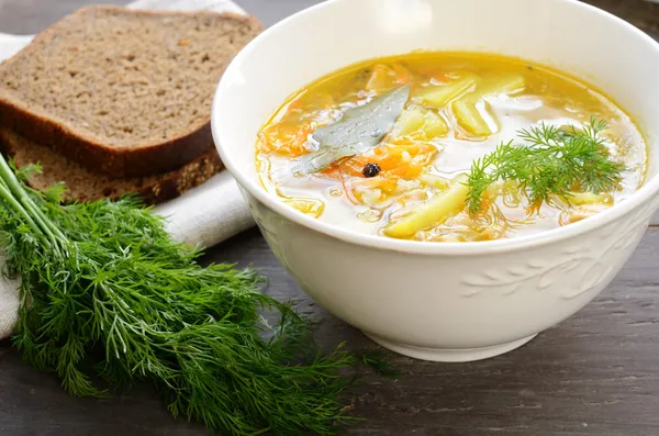 Skål med hemlagad fisksoppa serveras med mörkt bröd och dill — Stockfoto