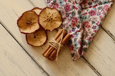 Dried apples and bunch cinnamon on wooden table clipart