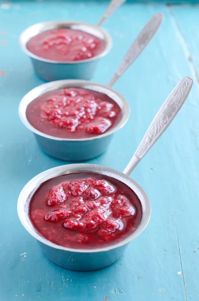 Raspberry sauсe on blue wooden background — Stock Photo, Image