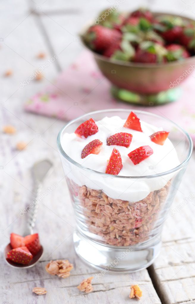 Muesli with cream and strawberry on wooden table
