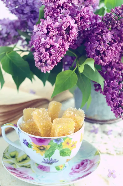 Stilleven met marmelade snoepjes en lila bloemen — Stockfoto