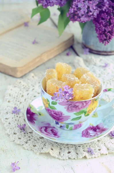 Stilleven met marmelade snoepjes en lila bloemen — Stockfoto