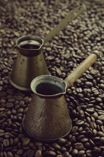 Два винтажных кофе cezve на фоне кофейных зерен — стоковое фото