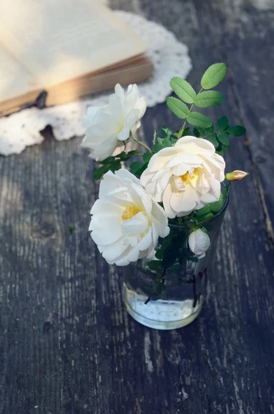 Dzika róża kwiaty w szklance na zardzewiałe drewniany stół — Zdjęcie stockowe