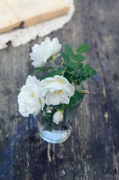 Dog rose květy ve sklenici na zrezivělý dřevěný stůl — Stock fotografie