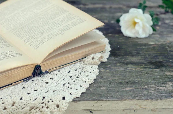 Aufgeschlagenes Buch auf Spitzendeckchen auf verrostetem Gartentisch — Stockfoto