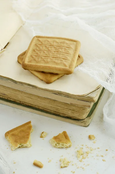 Two biscuits on vintage book pile — Stock Photo, Image