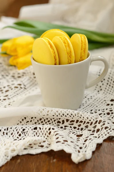 Copo com macaroon amarelo e tulipas amarelas no guardanapo de renda vintage — Fotografia de Stock