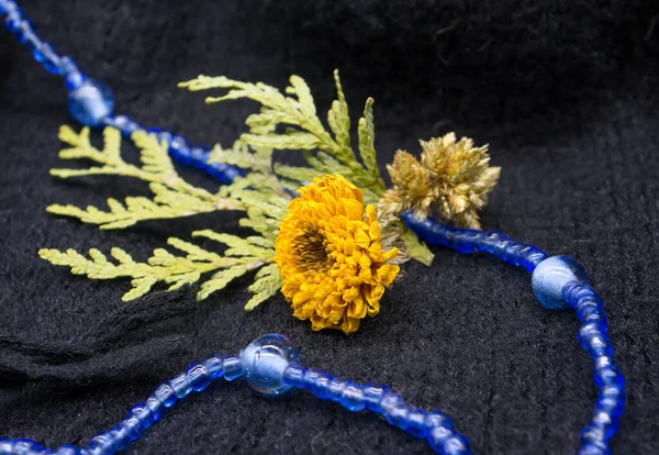 Hayat, kuru çiçekler ve siyah örülmüş arkaplanda mavi boncuklar.