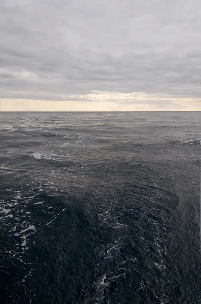 Een licht grijze lucht en het donker blauw-grijs zee — Stockfoto
