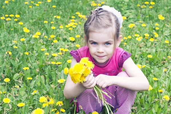 Jong meisje in een veld van paardebloemen — Stockfoto