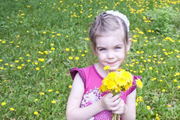 Jong meisje in een veld van paardebloemen — Stockfoto