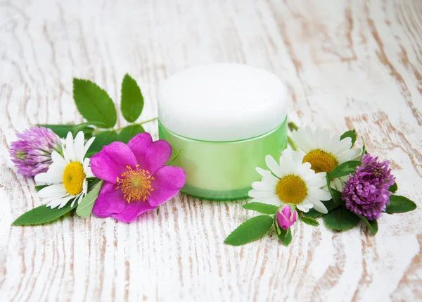 Container with cream and wild flowers — Stock Photo, Image