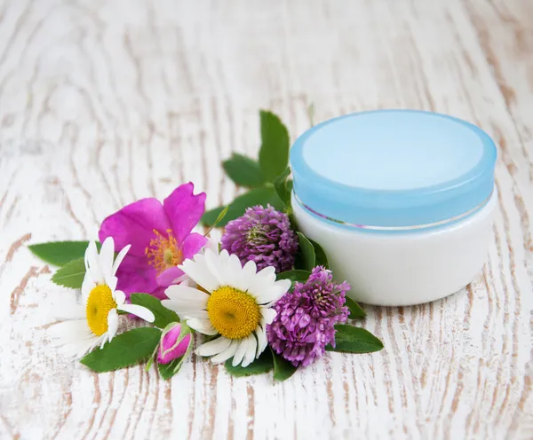 Container with cream and wild flowers — Stock Photo, Image