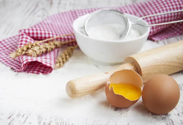 Flour and eggs on a wooden board — Stock Photo, Image