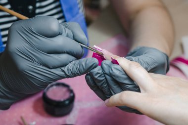 Manicurist makes nail extension for lower forms, close-up