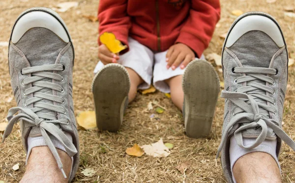 Sneakers front view of father sitting on field with his son — Stock Photo, Image
