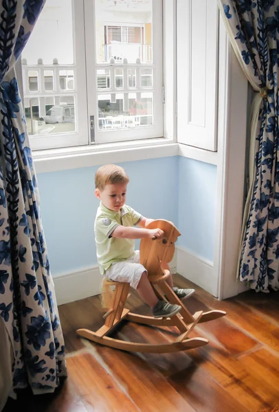 Pequeño niño montando en caballo mecedora vintage —  Fotos de Stock