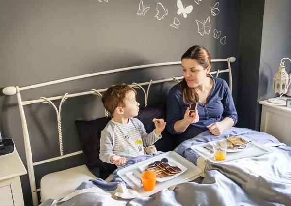 母亲和儿子在床上吃早餐 — 图库照片