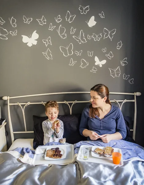 Mother and son having breakfast in bed — Stock Photo, Image