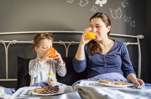 母亲和儿子在床上吃早餐 — 图库照片