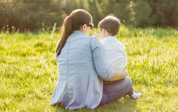 Cute son giving a bouquet of flowers to his mother sitting in a — Stock Photo, Image