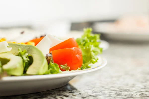 Close-up van salade met avocado, tomaat, sla, kaas en maïs — Stockfoto