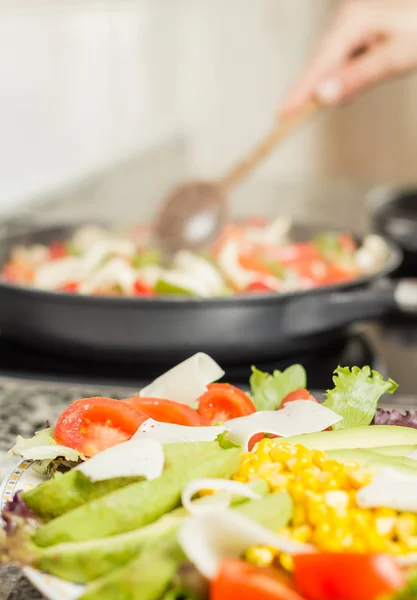 Close-up van verse salade schotel en vrouwelijke koken in een pan — Stockfoto