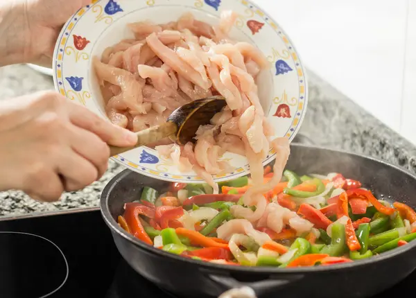 Close-up van kip in een pan en vrouwelijke koken groenten — Stockfoto