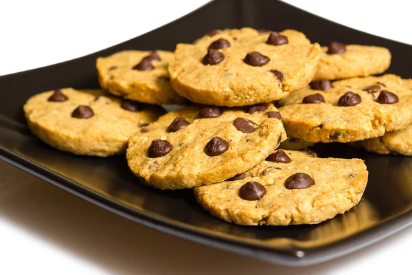 Biscotti con scaglie di cioccolato su una piastra nera isolata su dorso bianco — Foto Stock