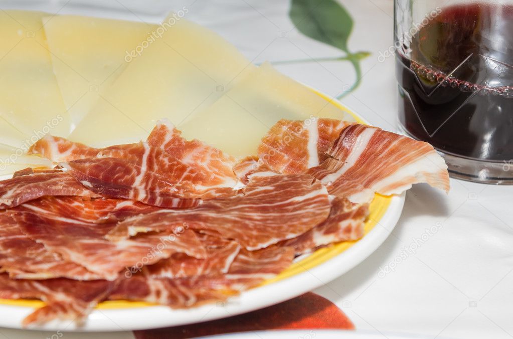 Typical spanish tapa with slices of serrano ham and manchego che