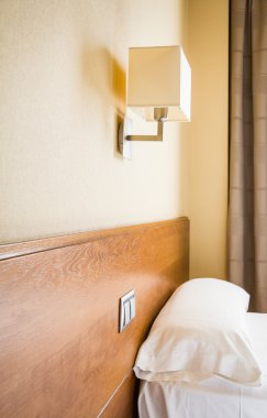 Hotel bedroom pillow and lamp in the wall clipart
