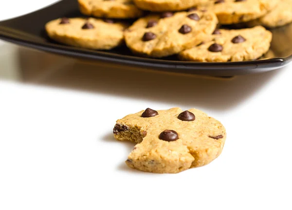 Bir ısırık ve bir tabak kurabiye yığını ile çikolatalı kurabiye — Stok fotoğraf