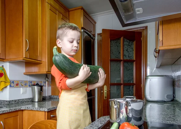 Cute child chef cooking big zucchini in a pot — Stock Photo, Image