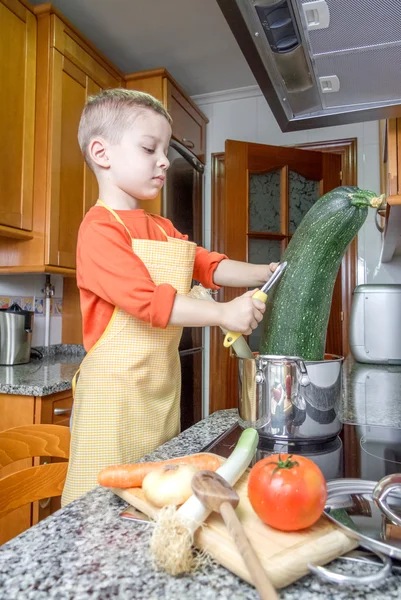 Schattig kind chef-kok koken grote courgette in een pot — Stockfoto