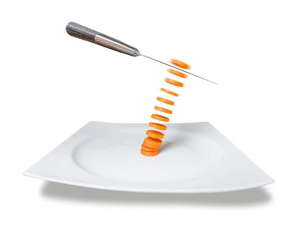 Couteau tranchant la carotte dans l'air sur la plaque — Photo