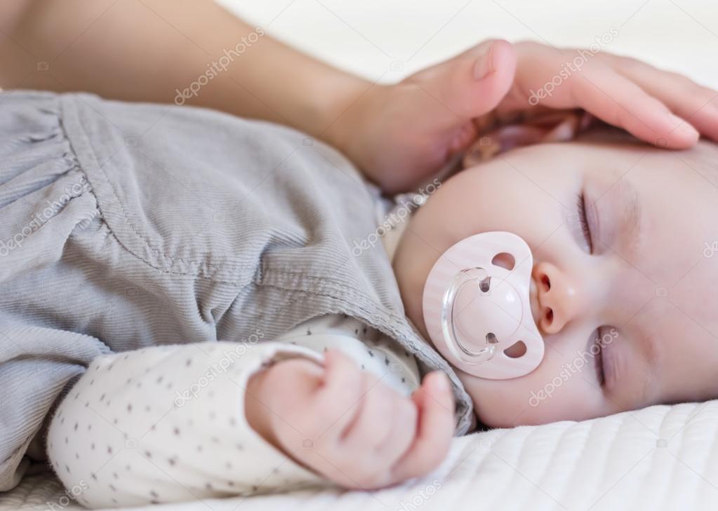 Hand of mother caressing her baby girl sleeping