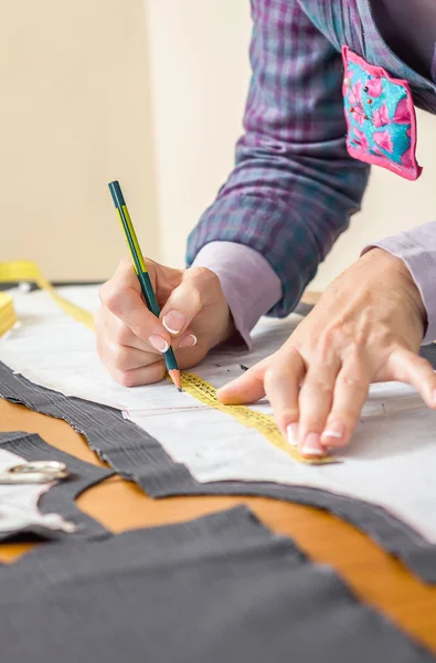 Dressmaker drawing tailor pattern on the table — Stock Photo, Image