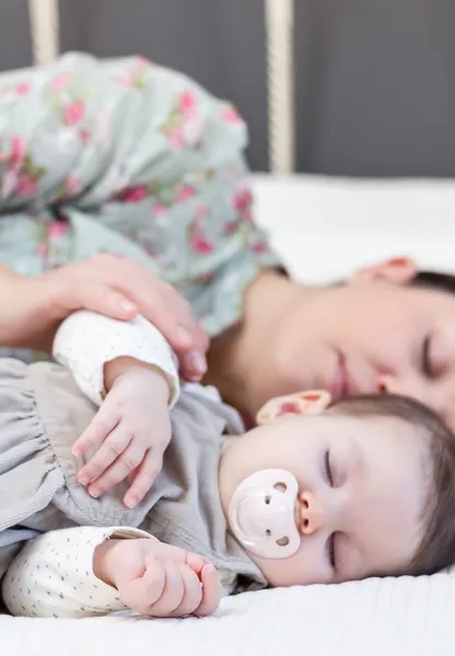 Jonge moeder en haar babymeisje slaapt in het bed — Stockfoto