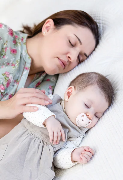 Jonge moeder en haar babymeisje slaapt in het bed — Stockfoto