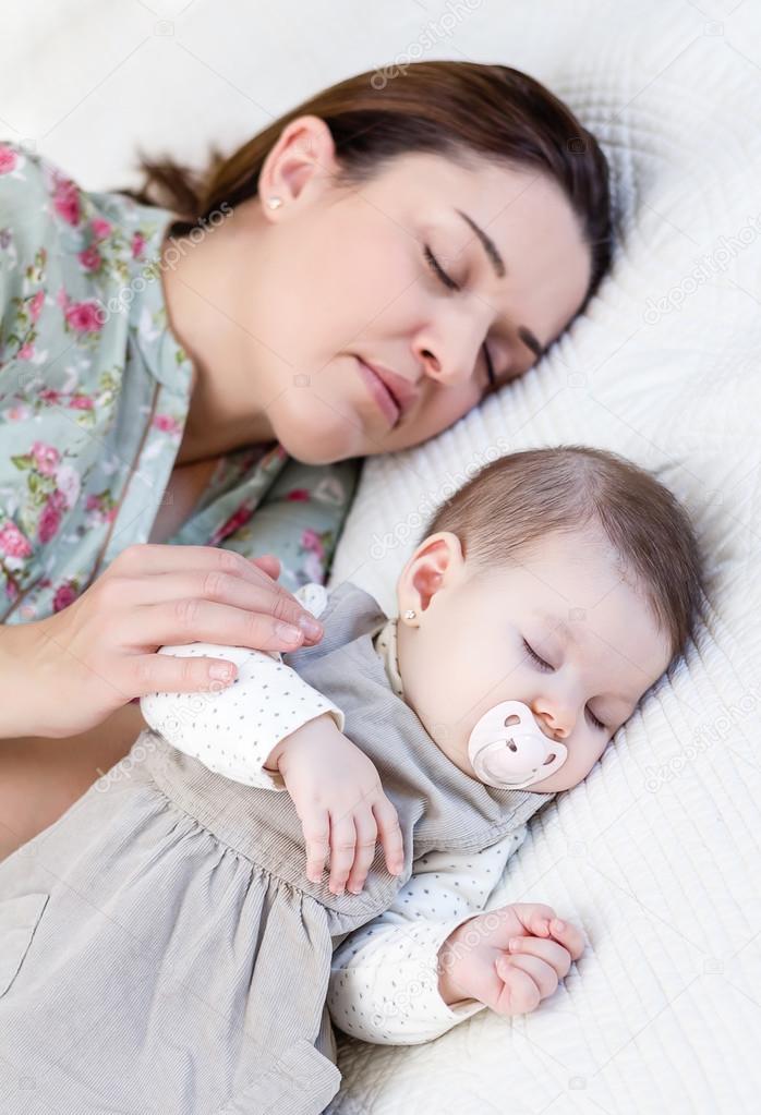Young mother and her baby girl sleeping in the bed