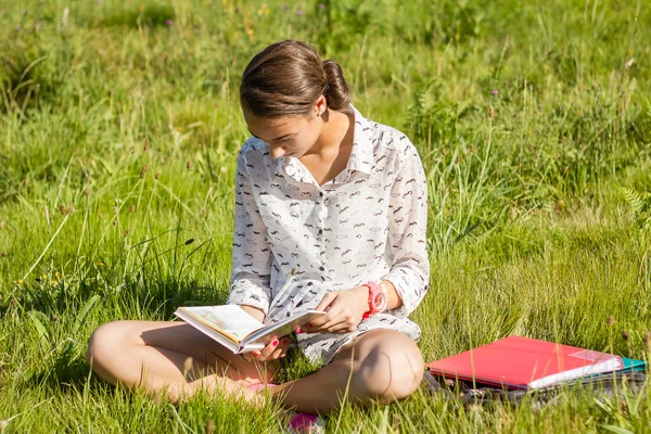 Vacker ung student som läser en bok i parken — Stockfoto