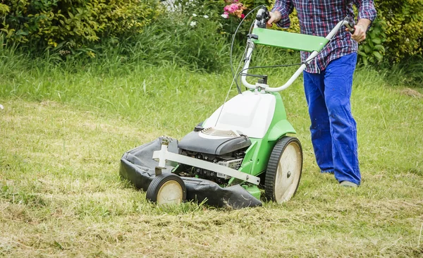 Joven cortando el césped con una cortadora de césped — Foto de Stock